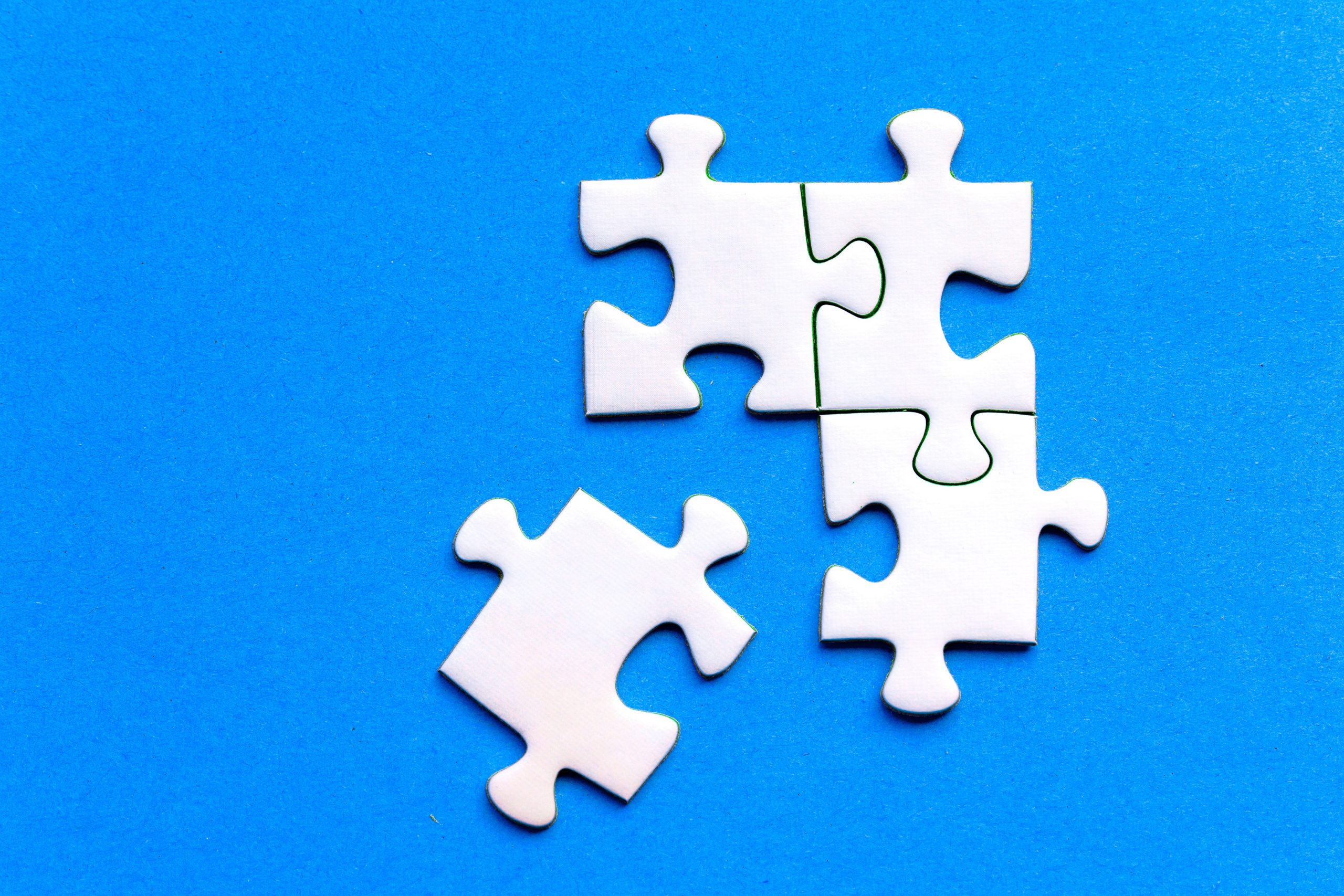 four white puzzle pieces on a blue background